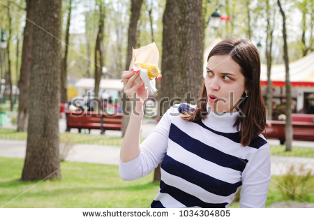 stock-photo-beautiful-girl-eating-delicious-corn-in-a-park-on-a-sunny-spring-day-having-fun-and-showing-theater-1034304805